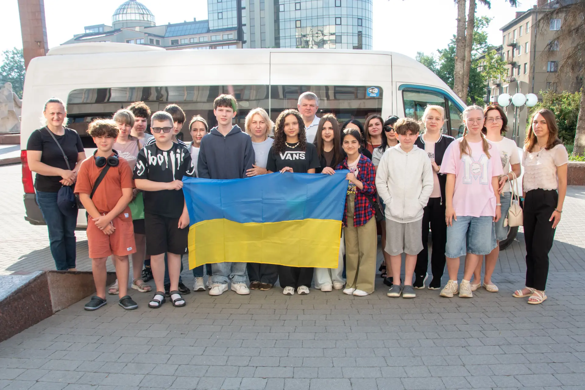 Група людей з українським прапором біля мікроавтобуса