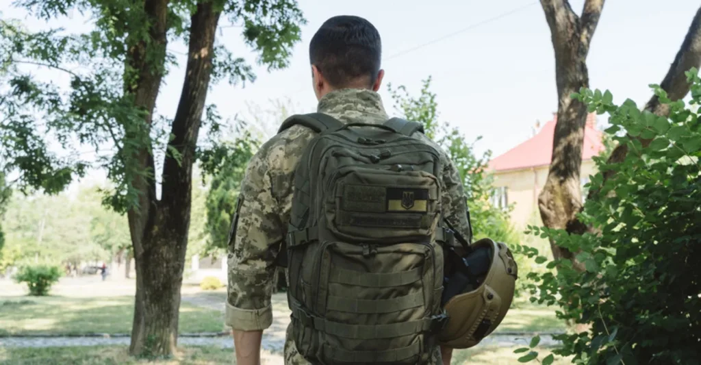 Військовий у формі з рюкзаком у парку