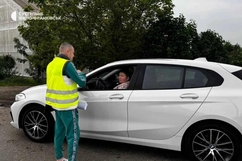 Волонтер спілкується з водієм білого автомобіля