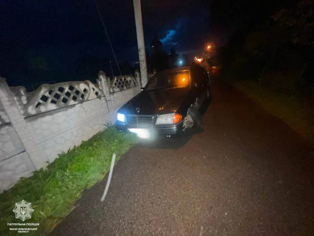 Автомобіль після ДТП біля паркану вночі