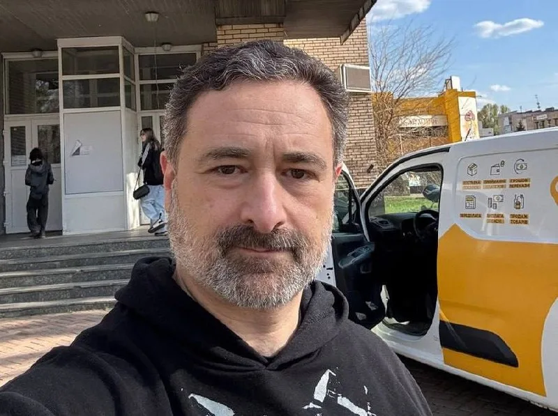 Чоловік робить селфі біля будівлі та авто