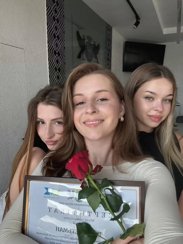 Три дівчини святкують отримання диплома з трояндою