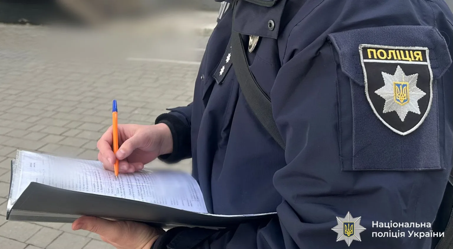 Поліцейський заповнює документи на вулиці