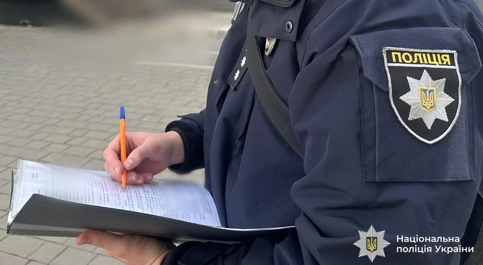 Поліцейський заповнює документи на вулиці