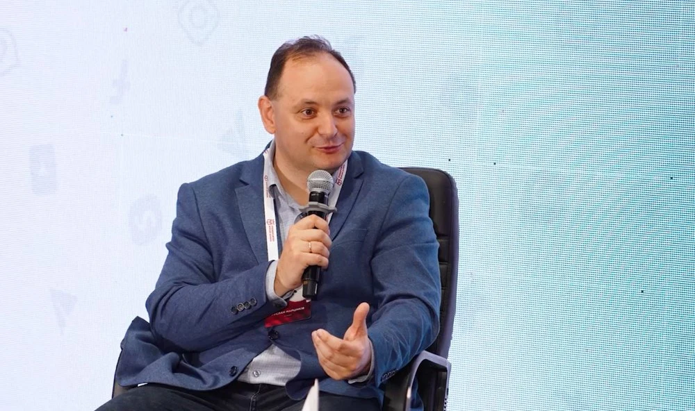 Чоловік у костюмі говорить у мікрофон на сцені
