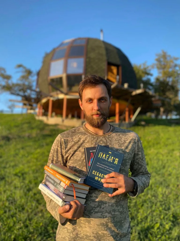 Чоловік тримає книги перед купольним будинком