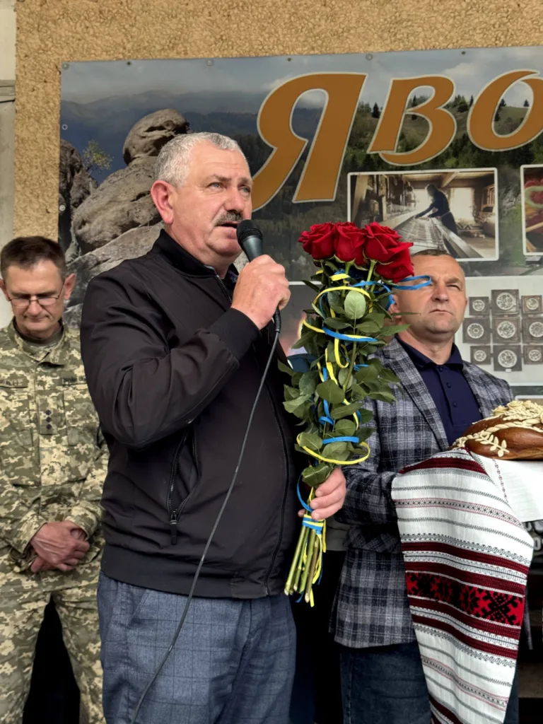 Чоловік з мікрофоном і квітами на святі