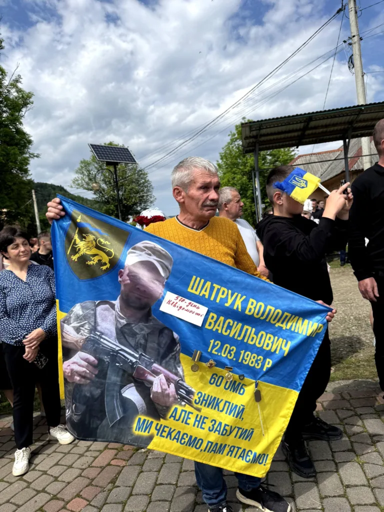 Люди тримають прапор на пам'ять про військового героя