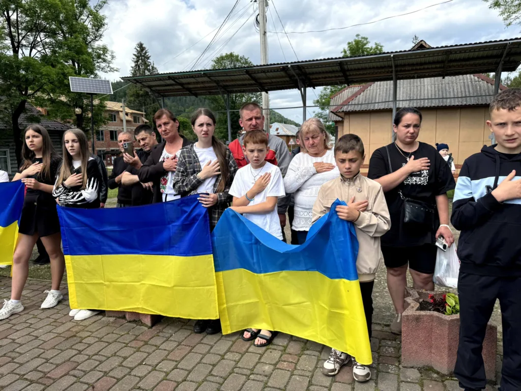 Люди тримають українські прапори під час церемонії