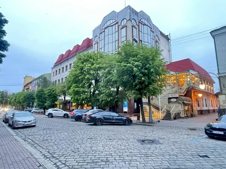 Вечірня вулиця з будівлями та припаркованими автомобілями