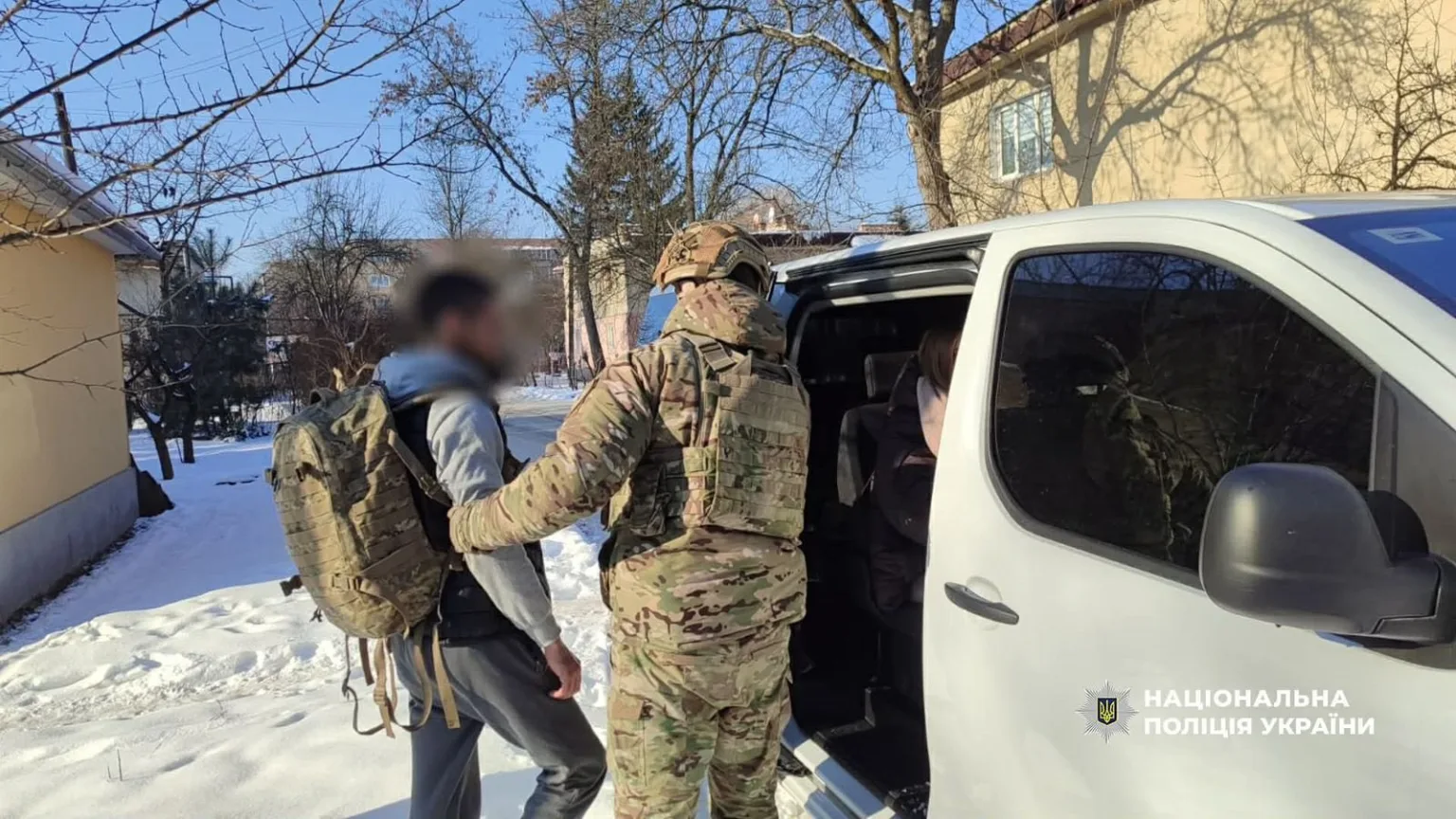 Поліцейський затримує чоловіка біля службового автомобіля