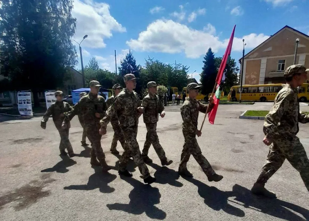 Військові у формі марширують із червоним прапором