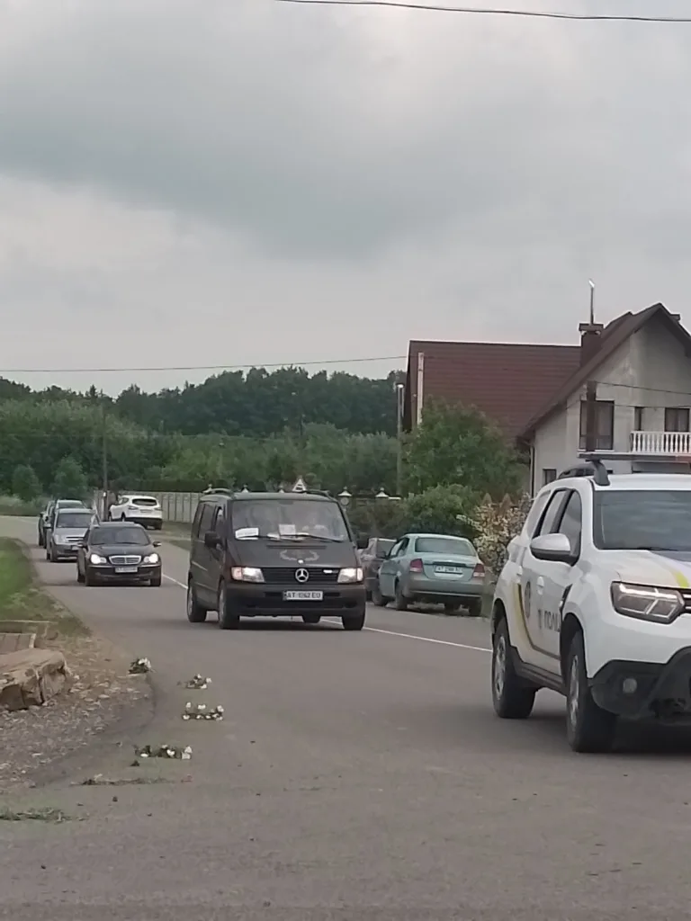 Автоколона рухається сільською дорогою біля будинку
