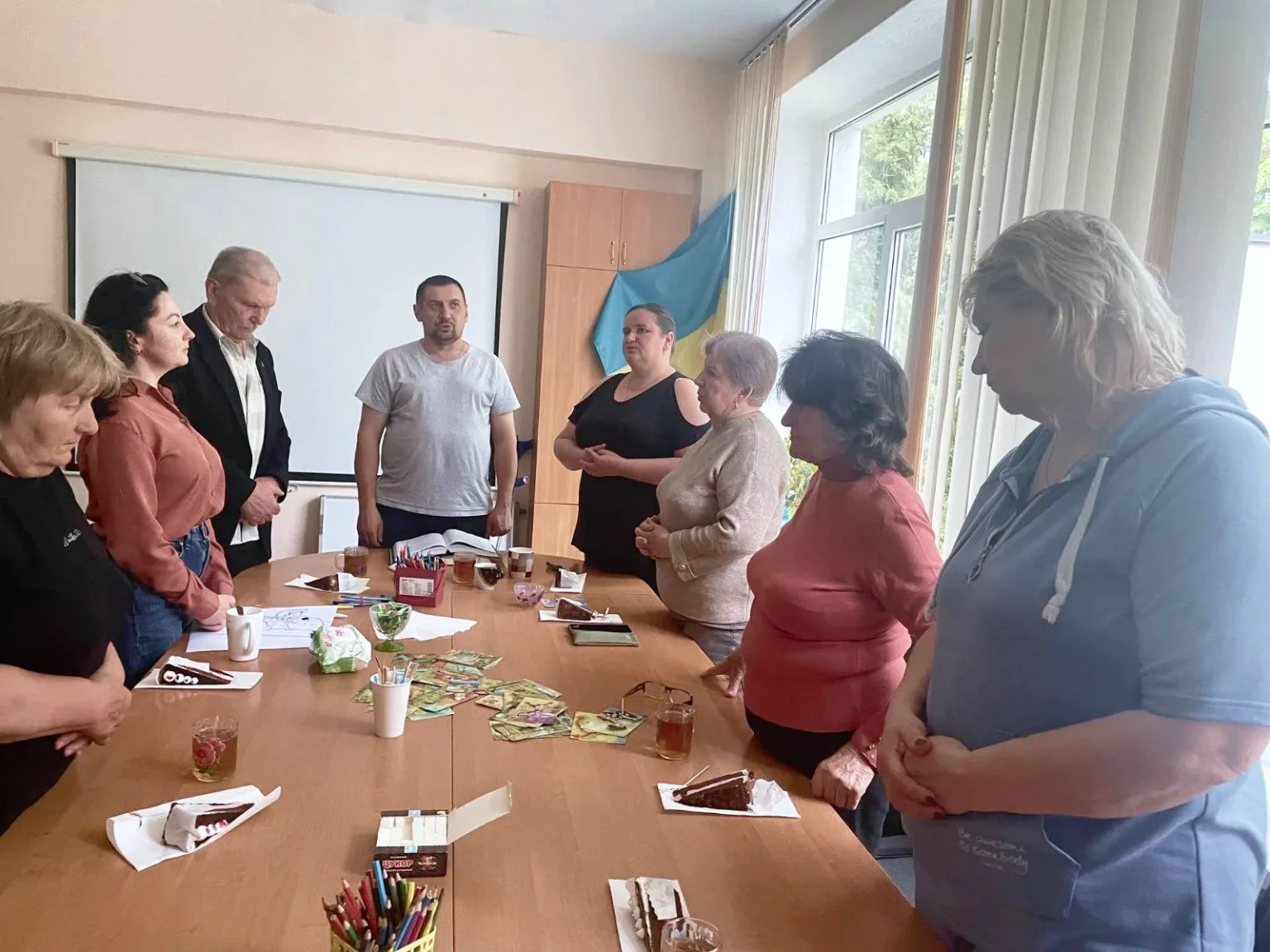 Група людей стоїть біля столу під час зустрічі