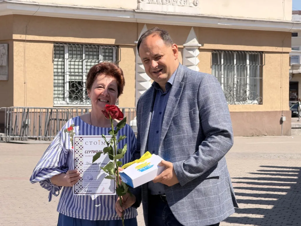 Жінка отримує сертифікат і квітку на вулиці