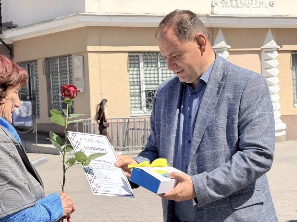 Чоловік вручає жінці сертифікат і квітку