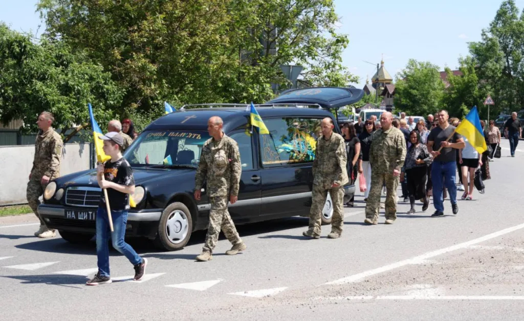 Похоронна процесія військових з українськими прапорами