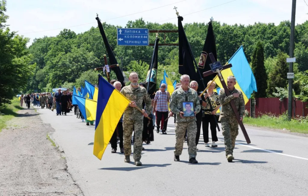 Процесія з українськими прапорами на дорозі