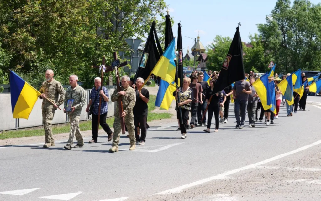 Похоронна процесія з українськими прапорами на вулиці