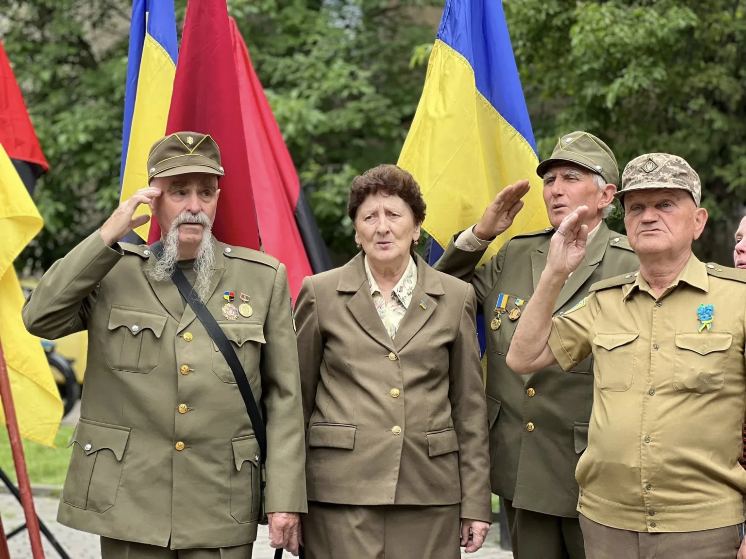 Ветерани у формі віддають честь під прапорами України