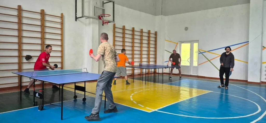 Люди грають у настільний теніс у спортзалі