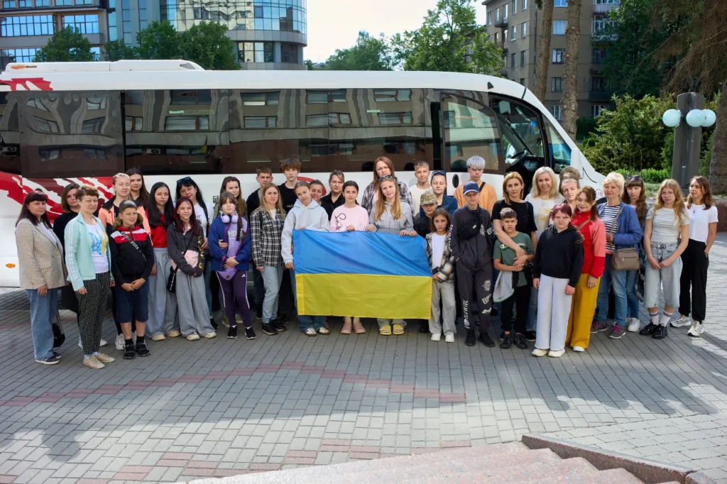 Група людей з українським прапором перед автобусом