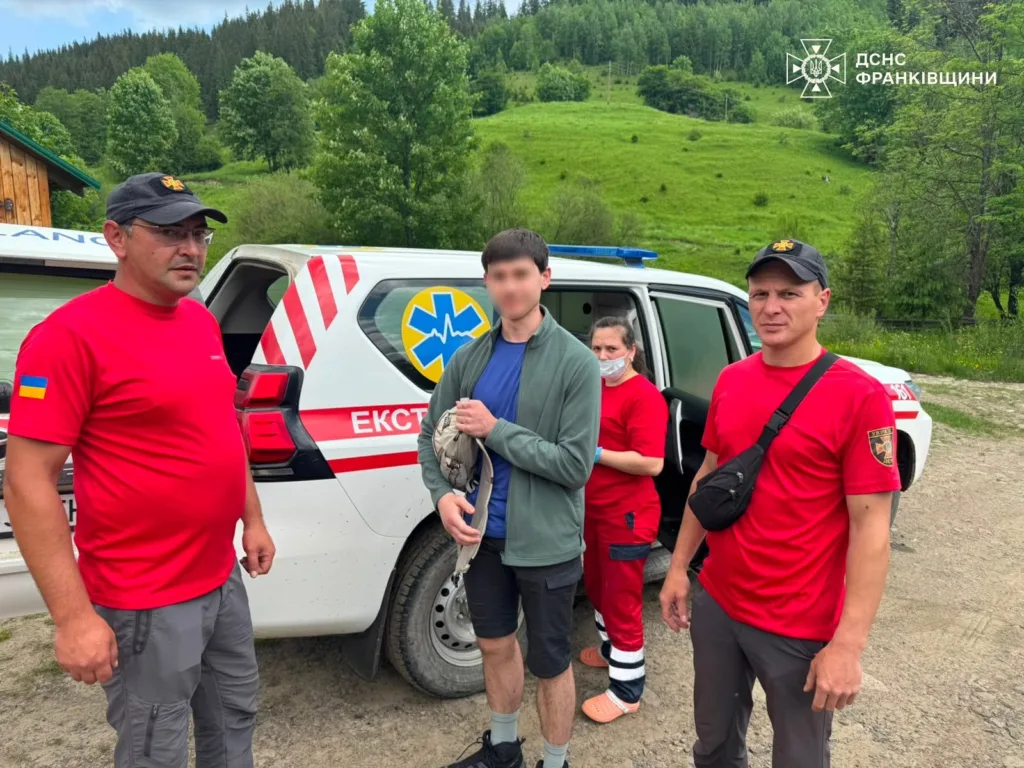Рятувальники допомагають туристу біля службового авто