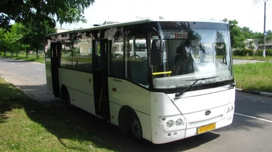 Білий міський автобус на зупинці біля дороги