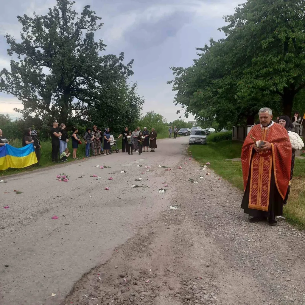 Священник і люди з українським прапором на дорозі