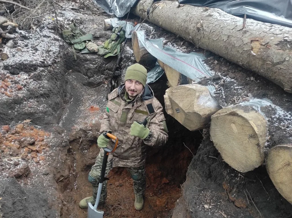 Військовий у бліндажі з лопатою взимку