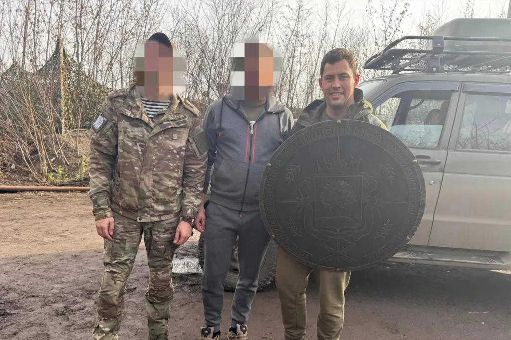 Військові тримають великий герб біля автомобіля