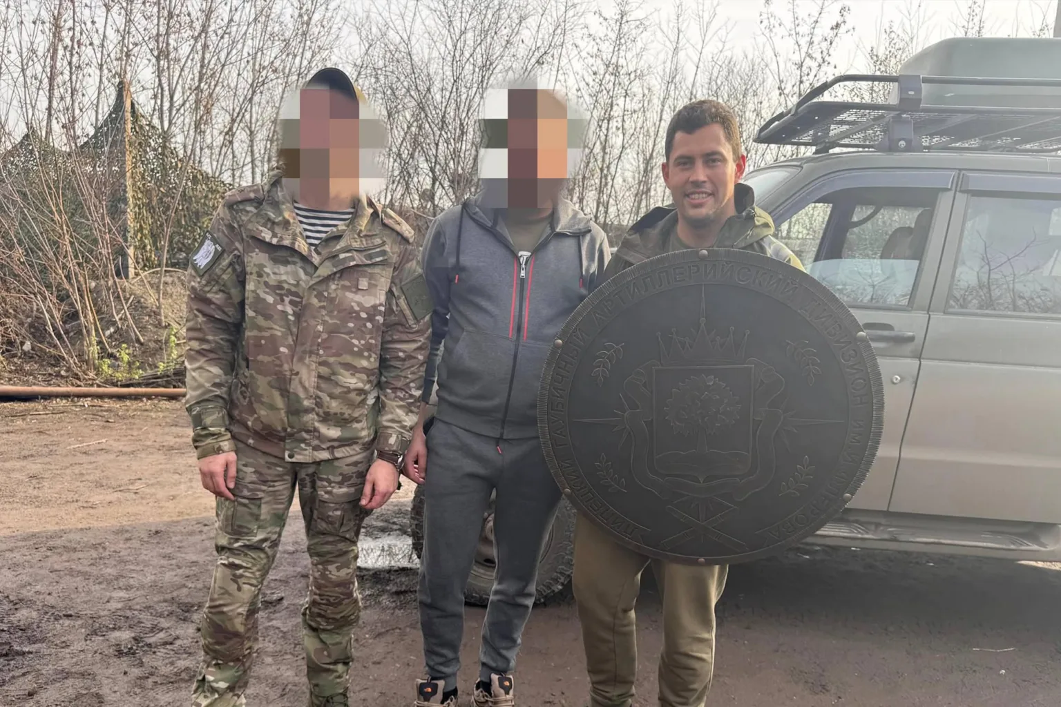 Військові тримають великий герб біля автомобіля