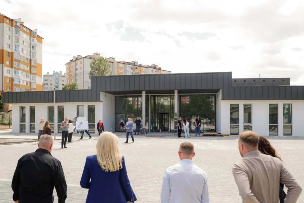 Люди перед новою сучасною будівлею в місті
