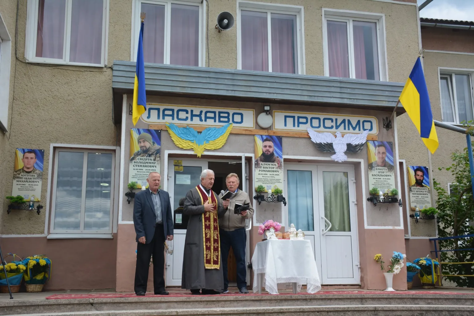 Церемонія перед будівлею з українськими прапорами