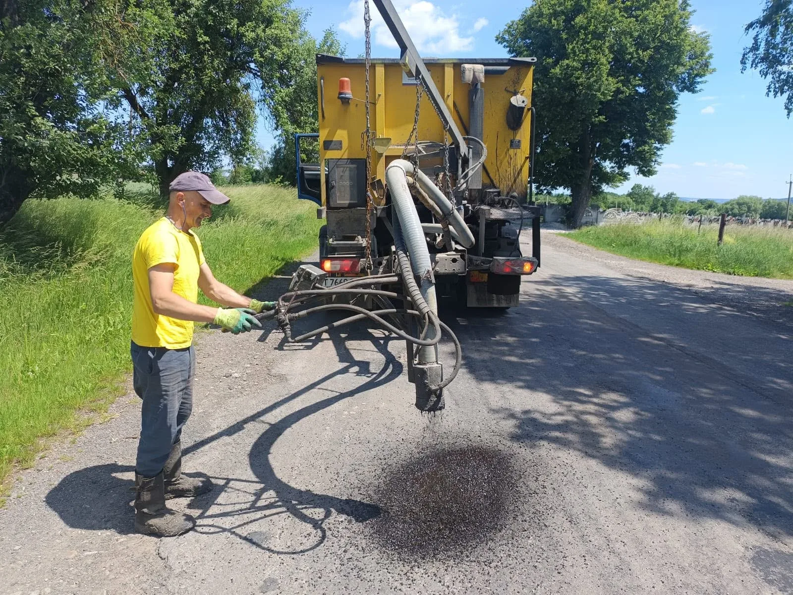 Робітник ремонтує асфальт сільської дороги