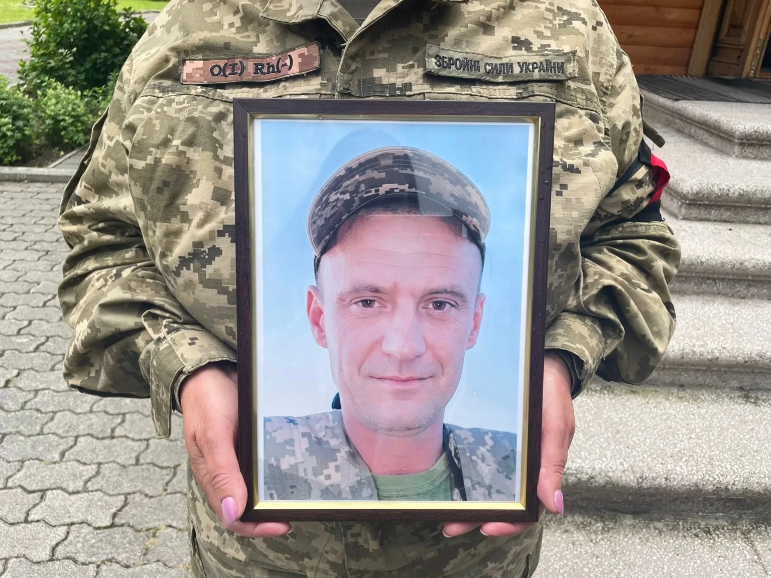Військовий тримає фотографію воїна в рамці