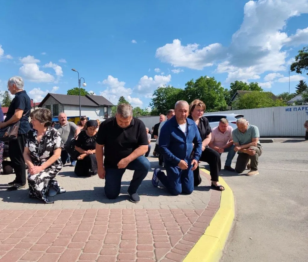 Люди стоять на колінах під час церемонії пам’яті