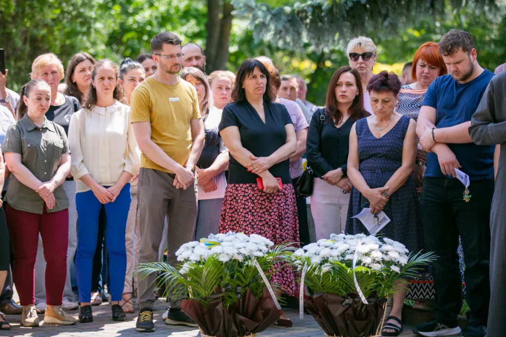 Люди стоять на церемонії покладання квітів