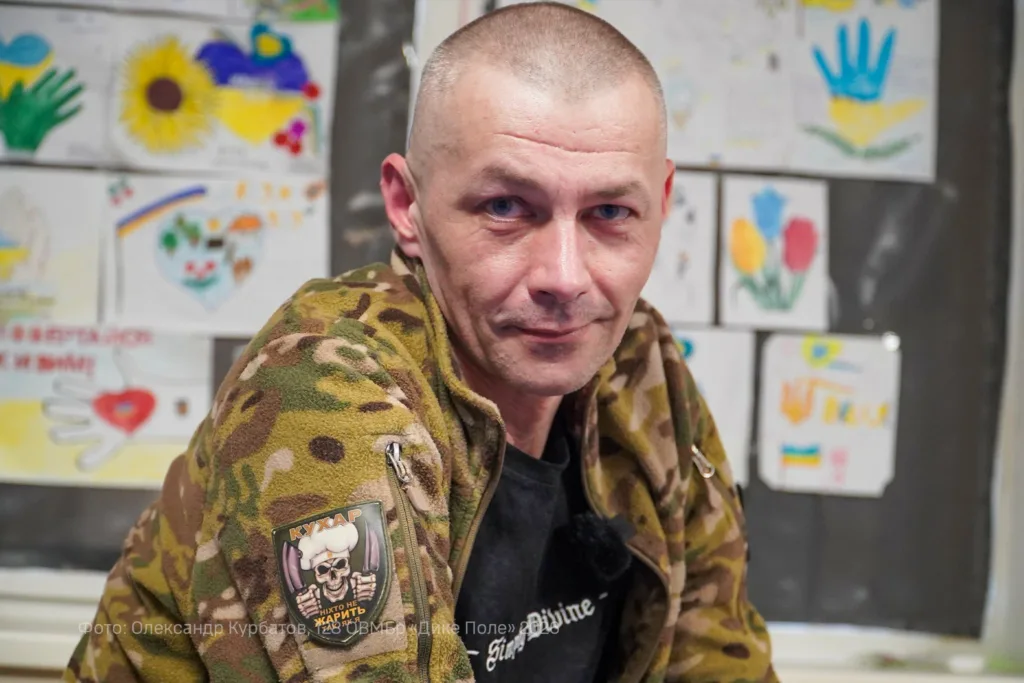 Військовий у камуфляжі на тлі дитячих малюнків