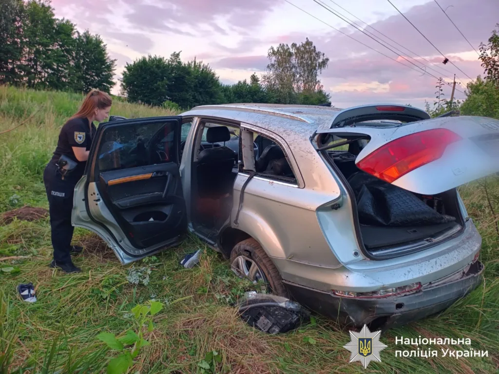 Поліцейська оглядає пошкоджений автомобіль після аварії
