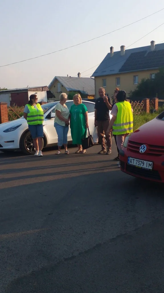 Люди спілкуються біля автомобілів на вулиці