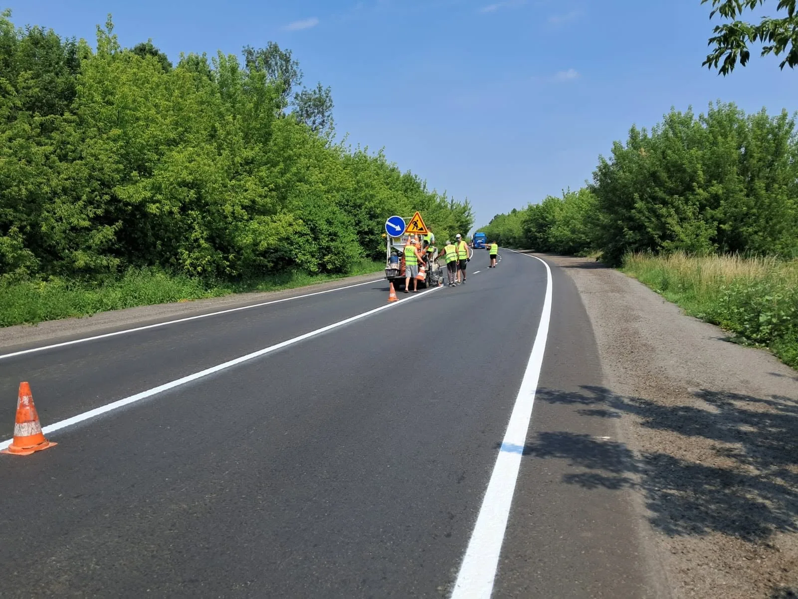 Розмітка нової дороги робітниками під сонцем