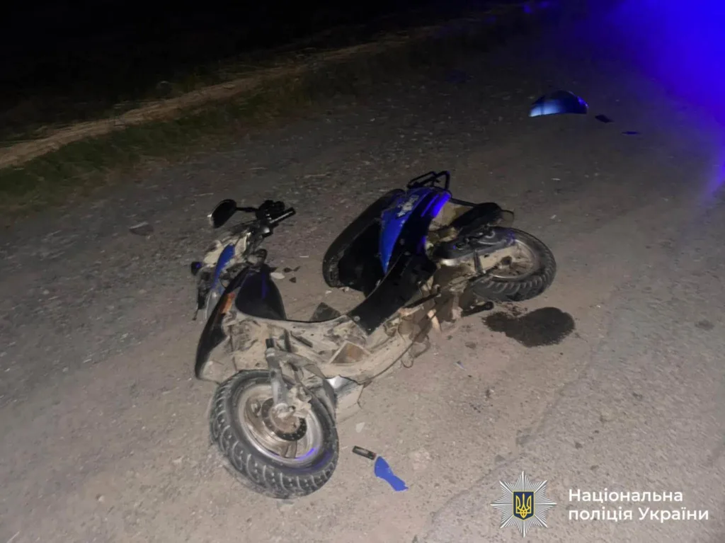 Пошкоджений мопед після аварії на нічній дорозі