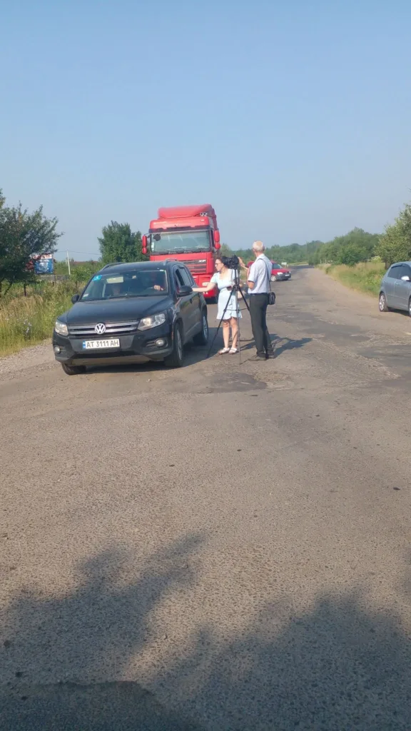 Журналісти знімають репортаж біля автомобіля на дорозі