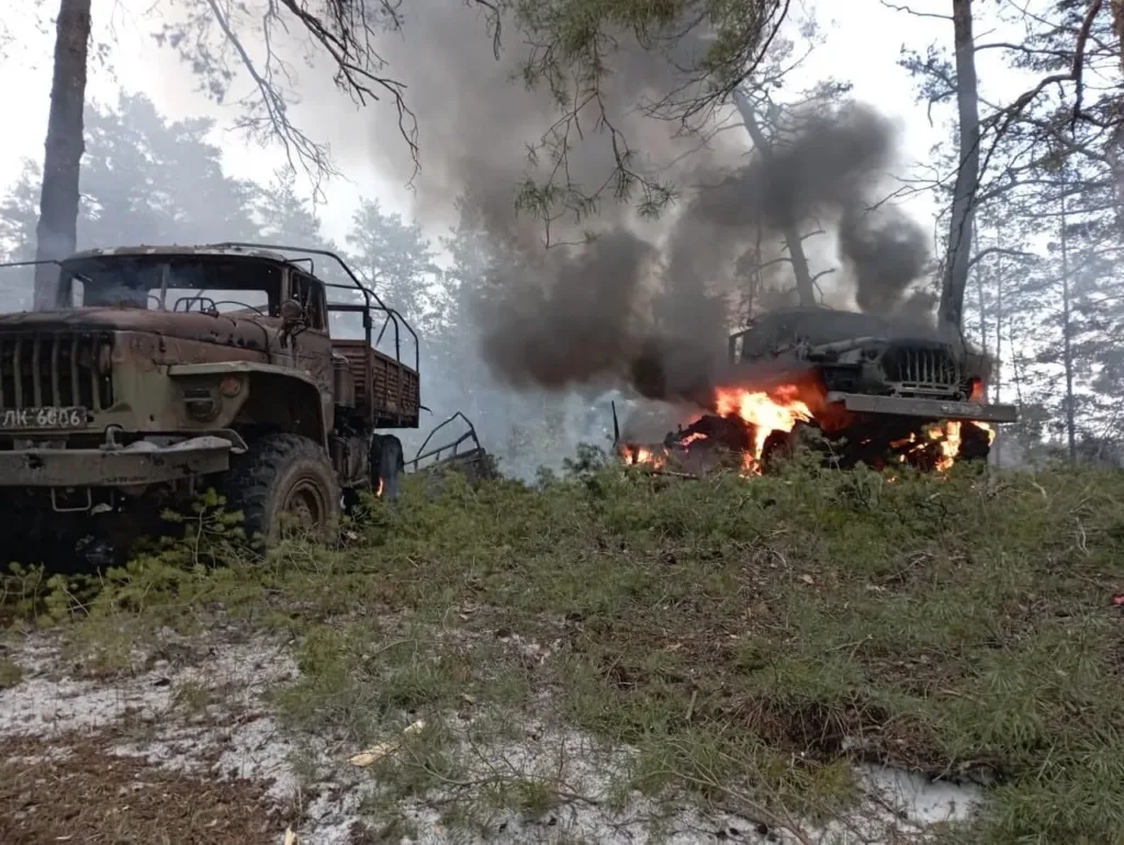Палаючі військові вантажівки в лісі