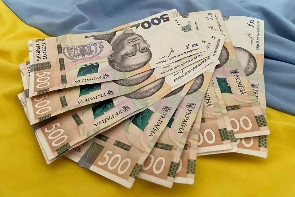 Пачка українських гривень на прапорі України