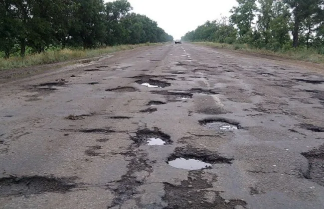 Пошкоджена дорога з численними вибоїнами