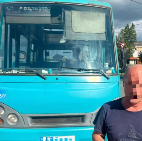 Чоловік стоїть перед синім автобусом