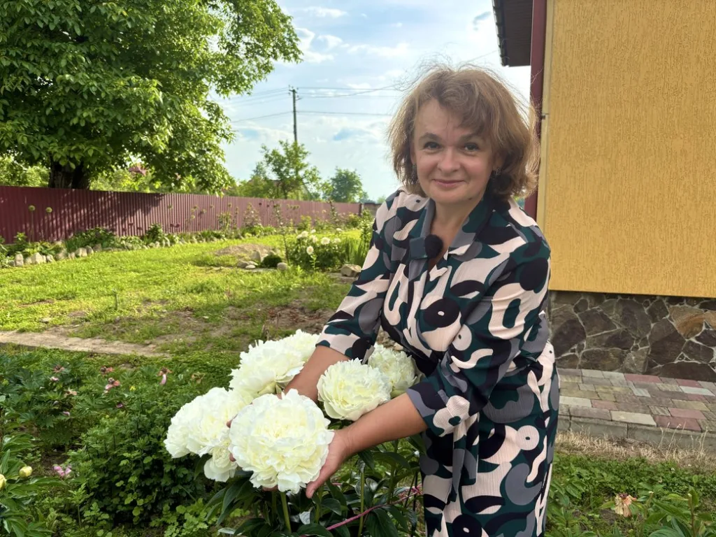 Жінка тримає білі півонії у саду
