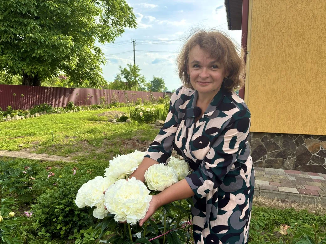 Жінка тримає білі півонії у саду